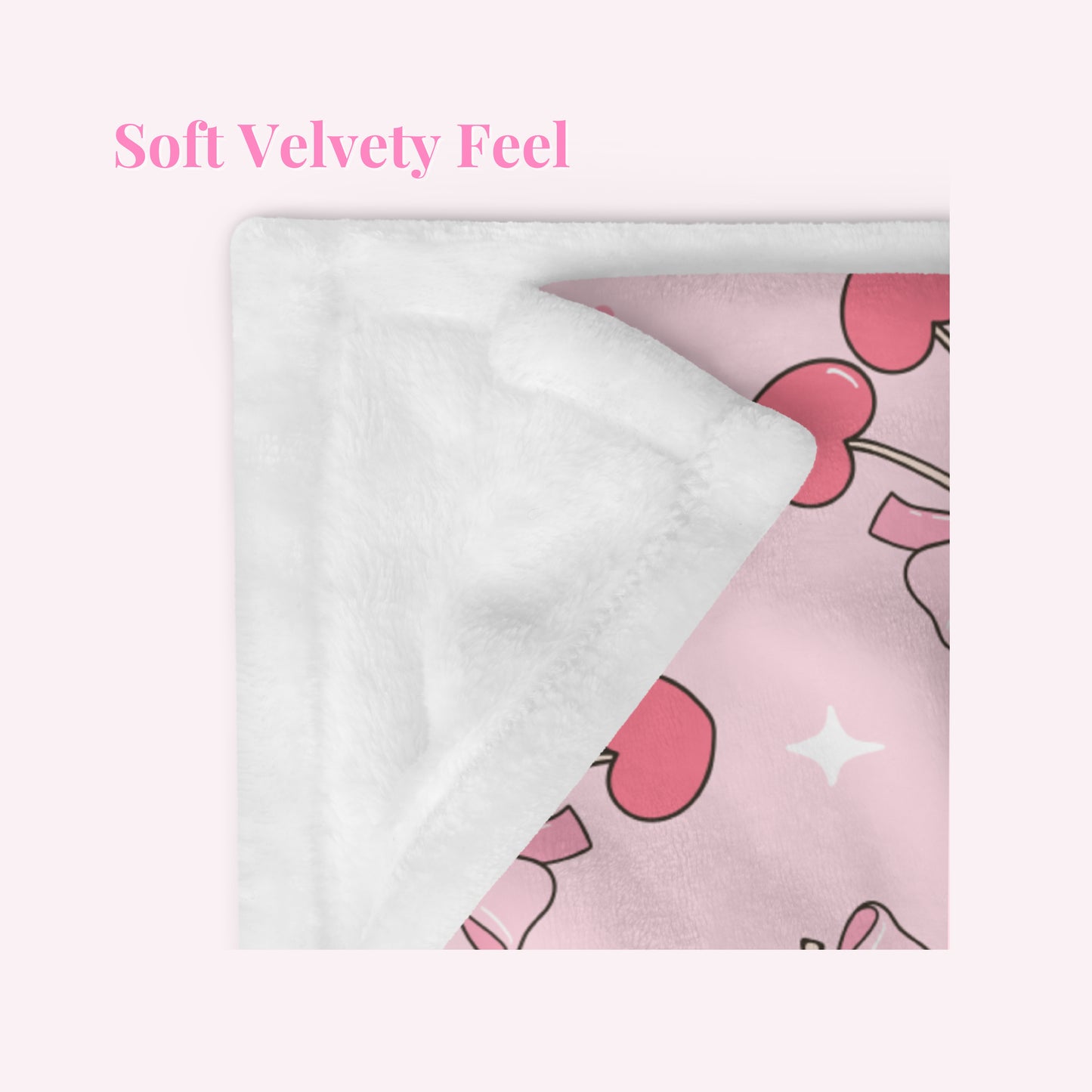 Close up of Pink velvety fabric with cherry and bow pattern design and white fluffy fabric underneath, labeled 'Soft Velvety Feel'.