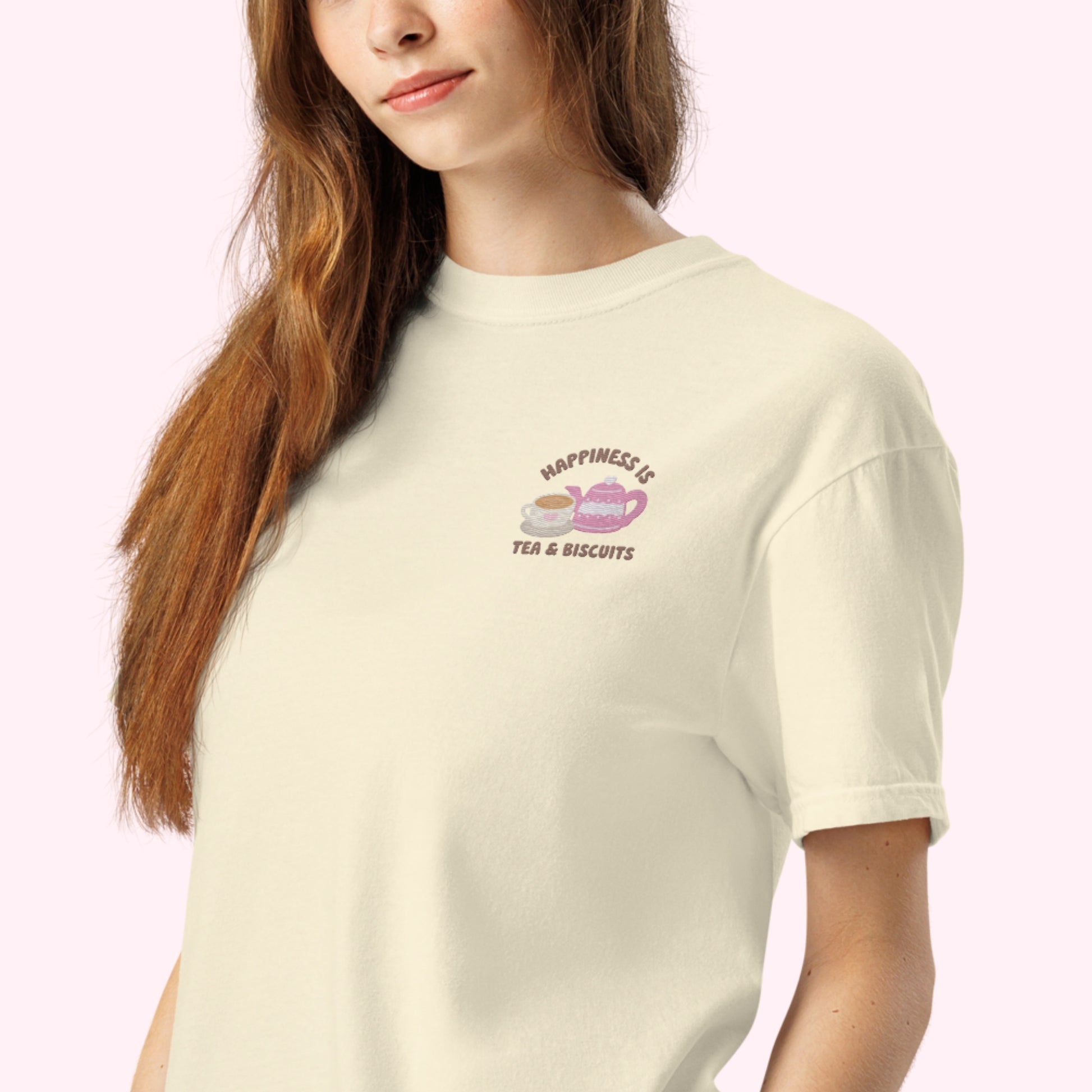 Close-up of "Happiness is Tea and Biscuits" script with a tiny embroidered teacup and teapot on a ivory-coloured t-shirt.