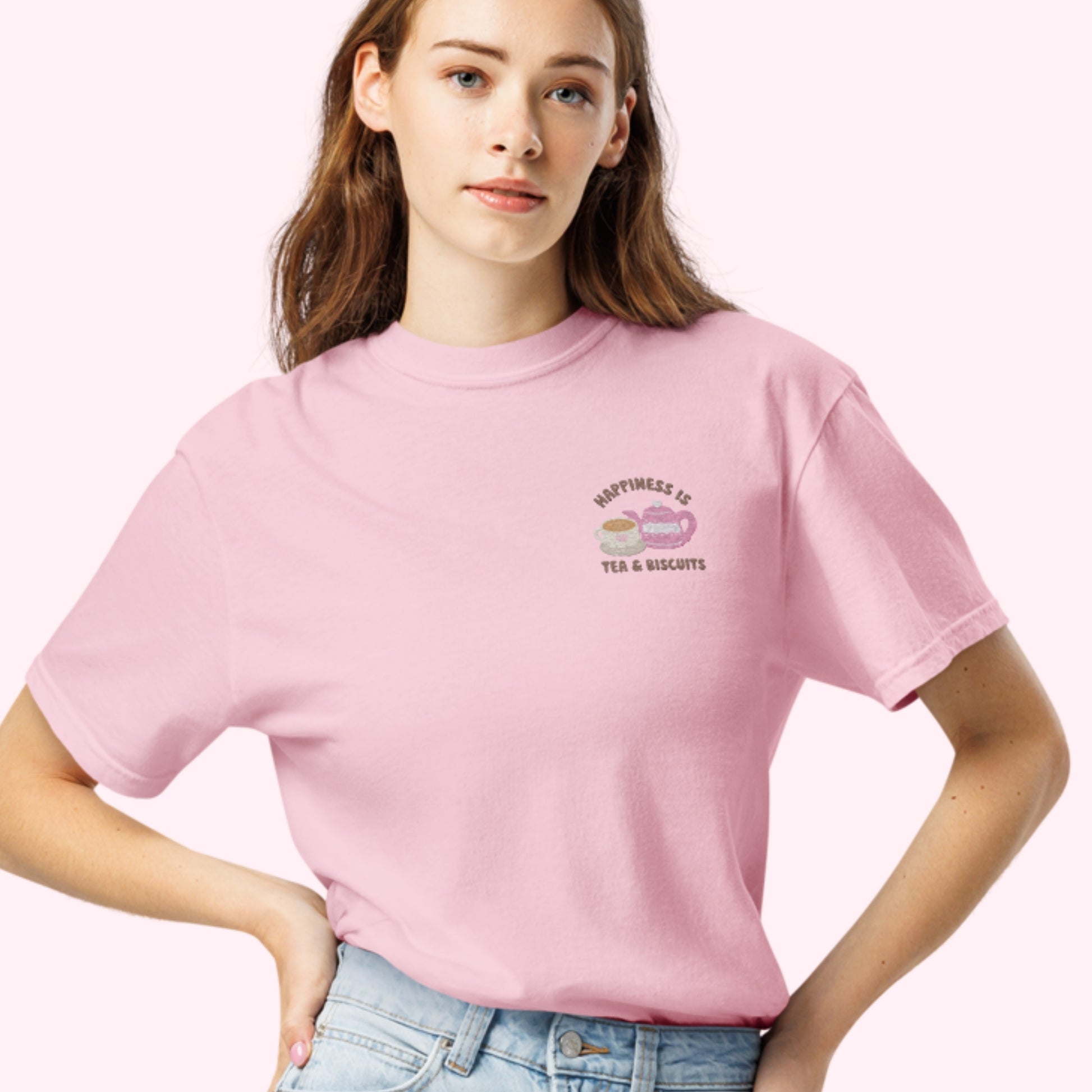 Close-up of "Happiness is Tea and Biscuits" script with a tiny embroidered teacup and teapot on a pink-colored t-shirt. cottagecore cozy girl slow life tee
