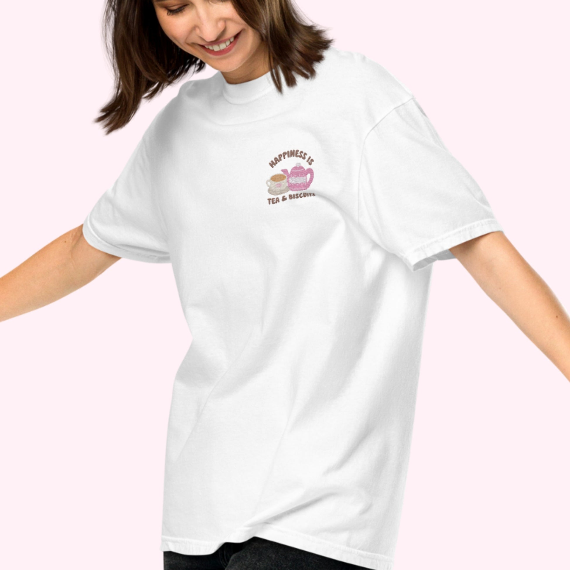 Close-up of "Happiness is Tea and Biscuits" script with a tiny embroidered teacup and teapot on a white-coloured t-shirt. cozy girl vibes