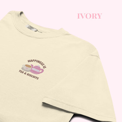 Close-up of "Happiness is Tea and Biscuits" script with a tiny embroidered teacup and teapot on a ivory-coloured t-shirt.