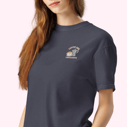 Embroidered navy tshirt with coffee and croissant text and a cute coffee mug and grey stove top coffee maker. slow cozy moments. coffee lover gift