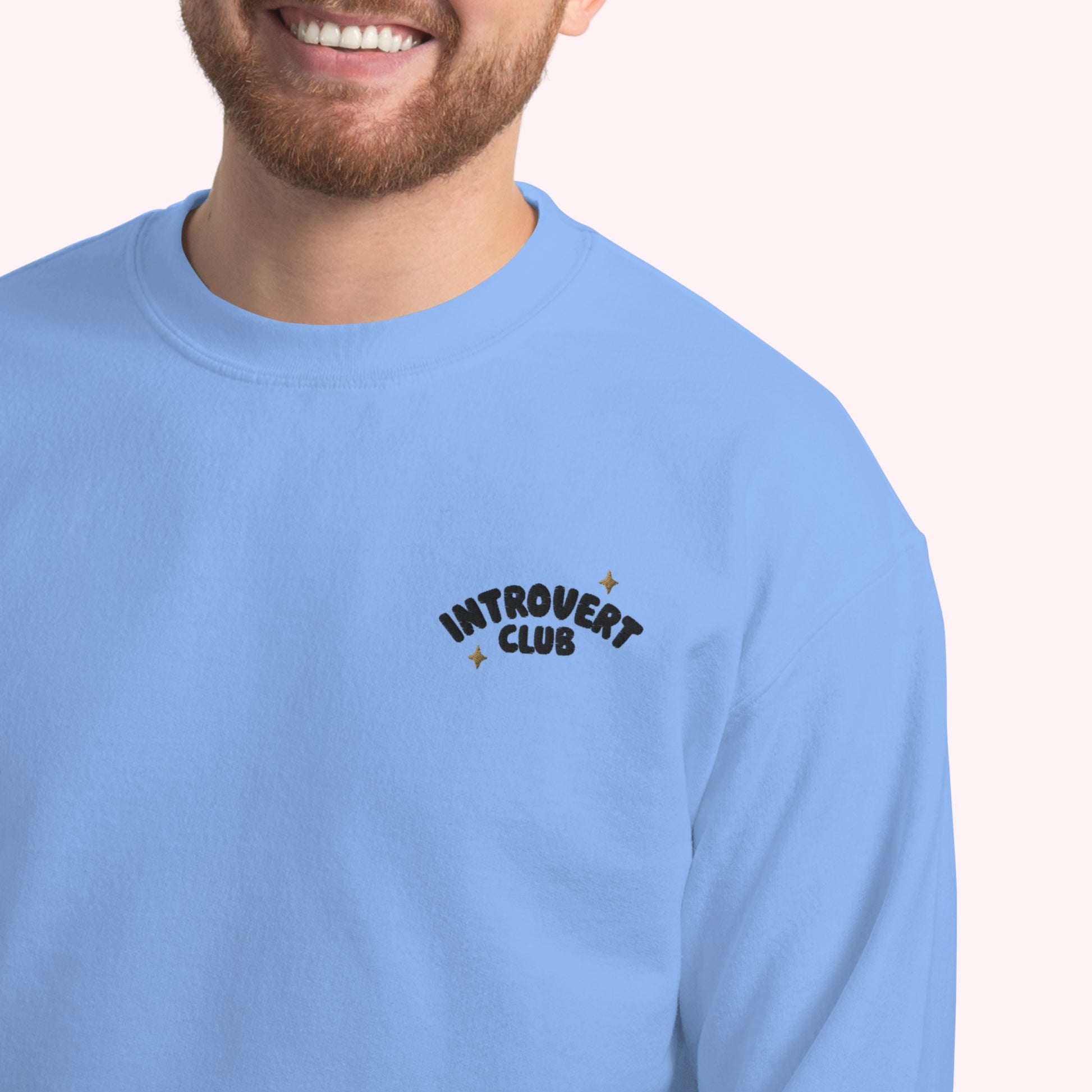 Person wearing a light blue sweatshirt with 'Introvert Club' text on a plain background
