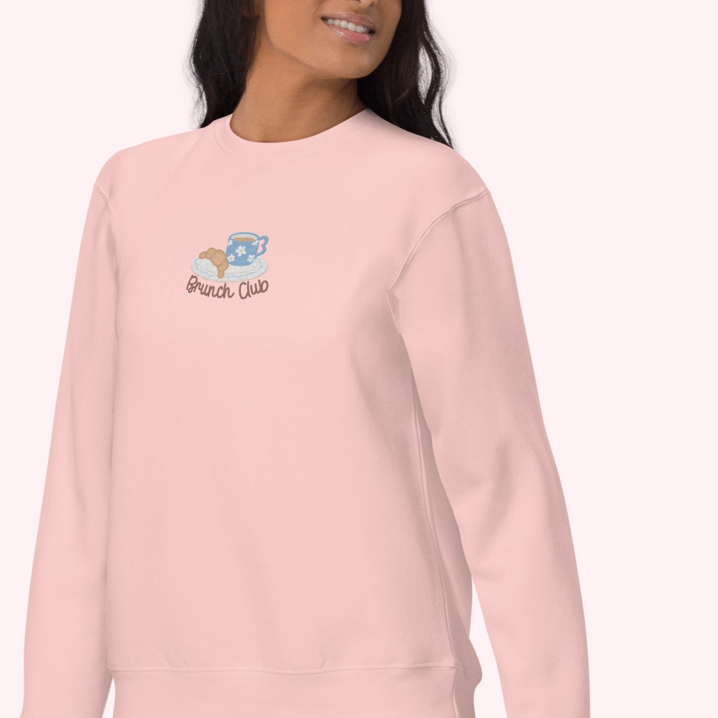 women wearing a pink sweatshirt with a embroidered design. Brunch club, croissant and coffee cozy slow life design
