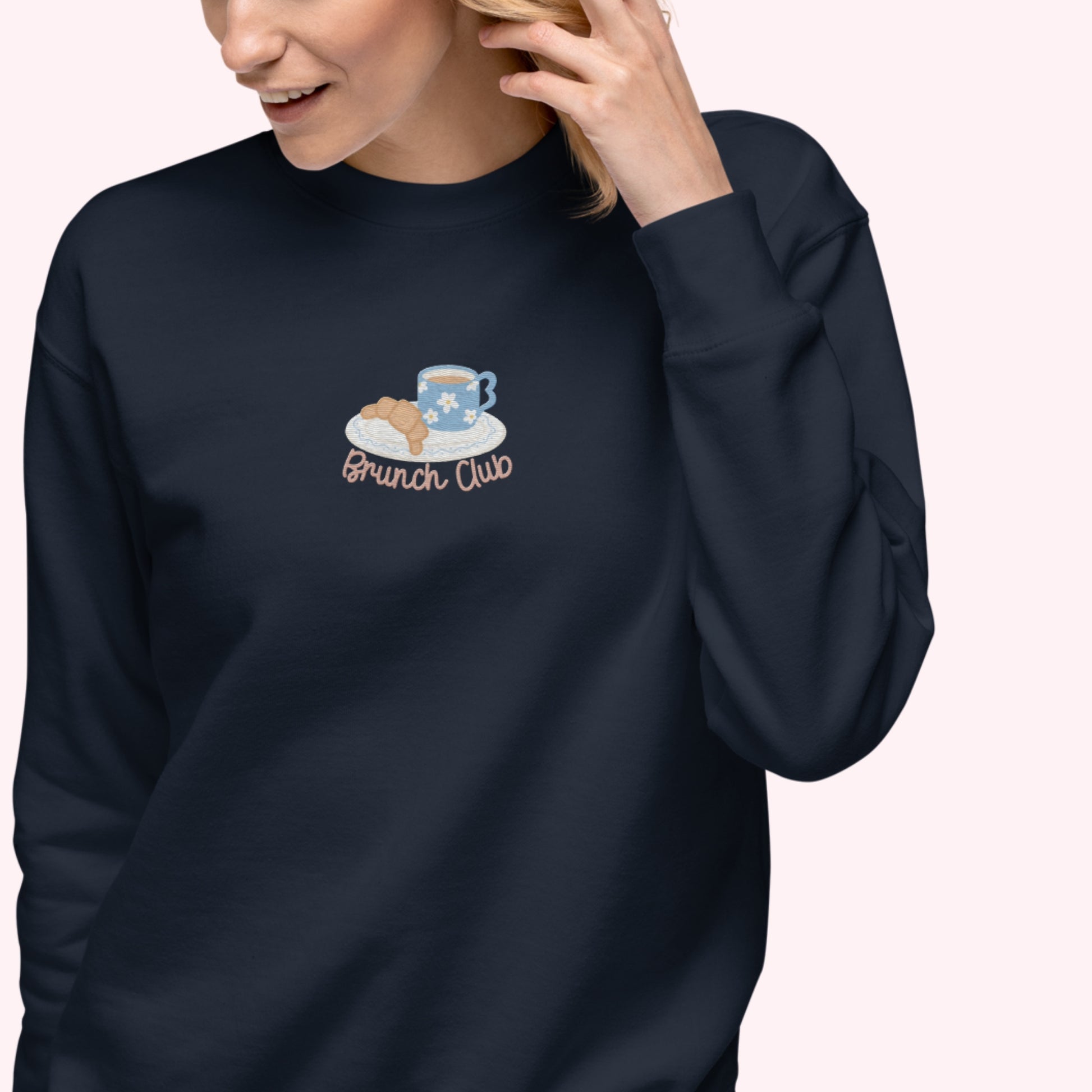 Person wearing a navy blue sweatshirt with 'Brunch Club' design on a white background