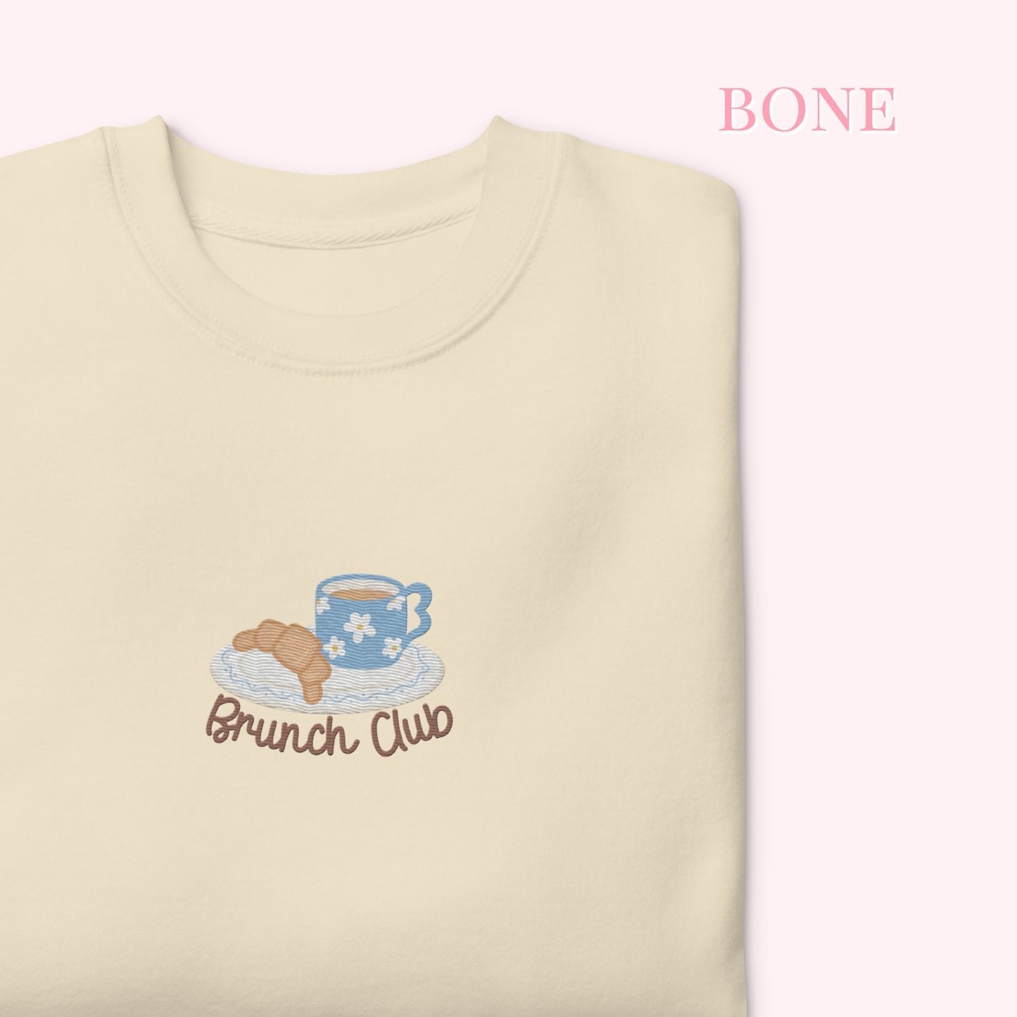 Beige sweatshirt with 'Brunch Club' embroidery featuring a coffee cup and pastry on a white background.
