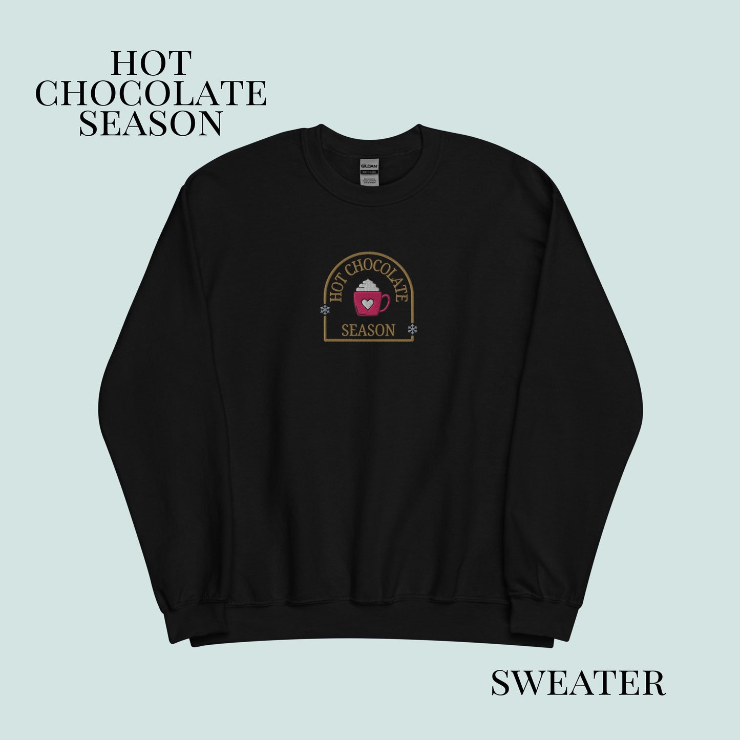 Black sweater with 'Hot Chocolate Season' logo on a light blue background