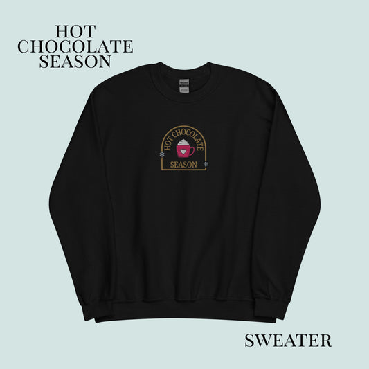 Black sweater with 'Hot Chocolate Season' logo on a light blue background