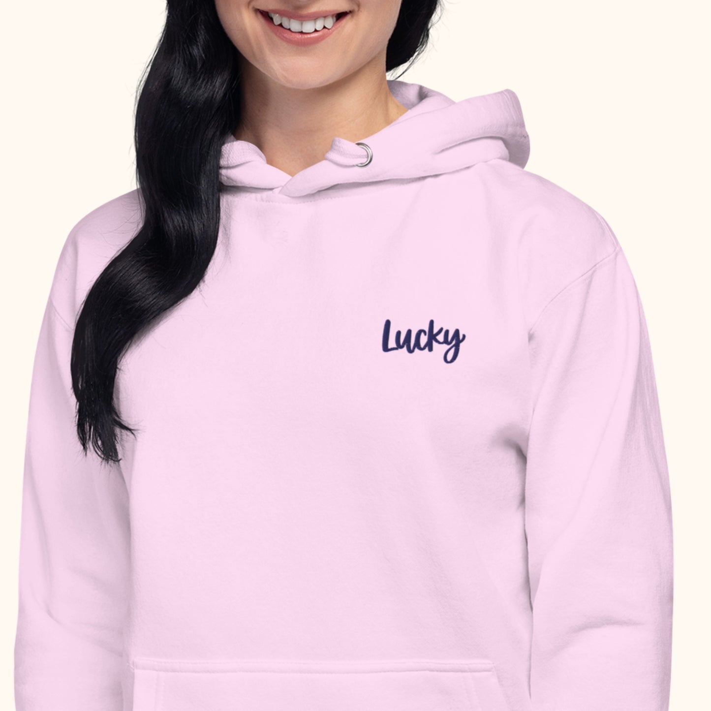 women wearing a light pink hoodie with 'Lucky' text on a white background