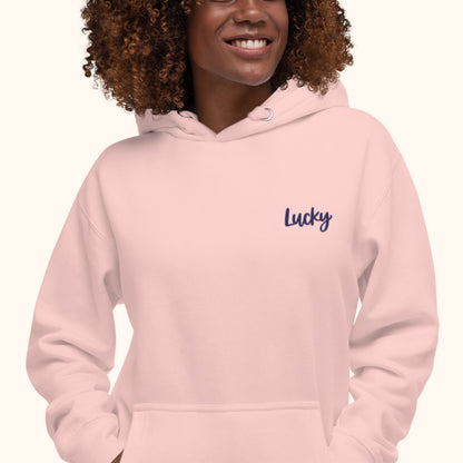 women wearing a pink hoodie with 'Lucky' embroidered text on a white background lucky charm hoody