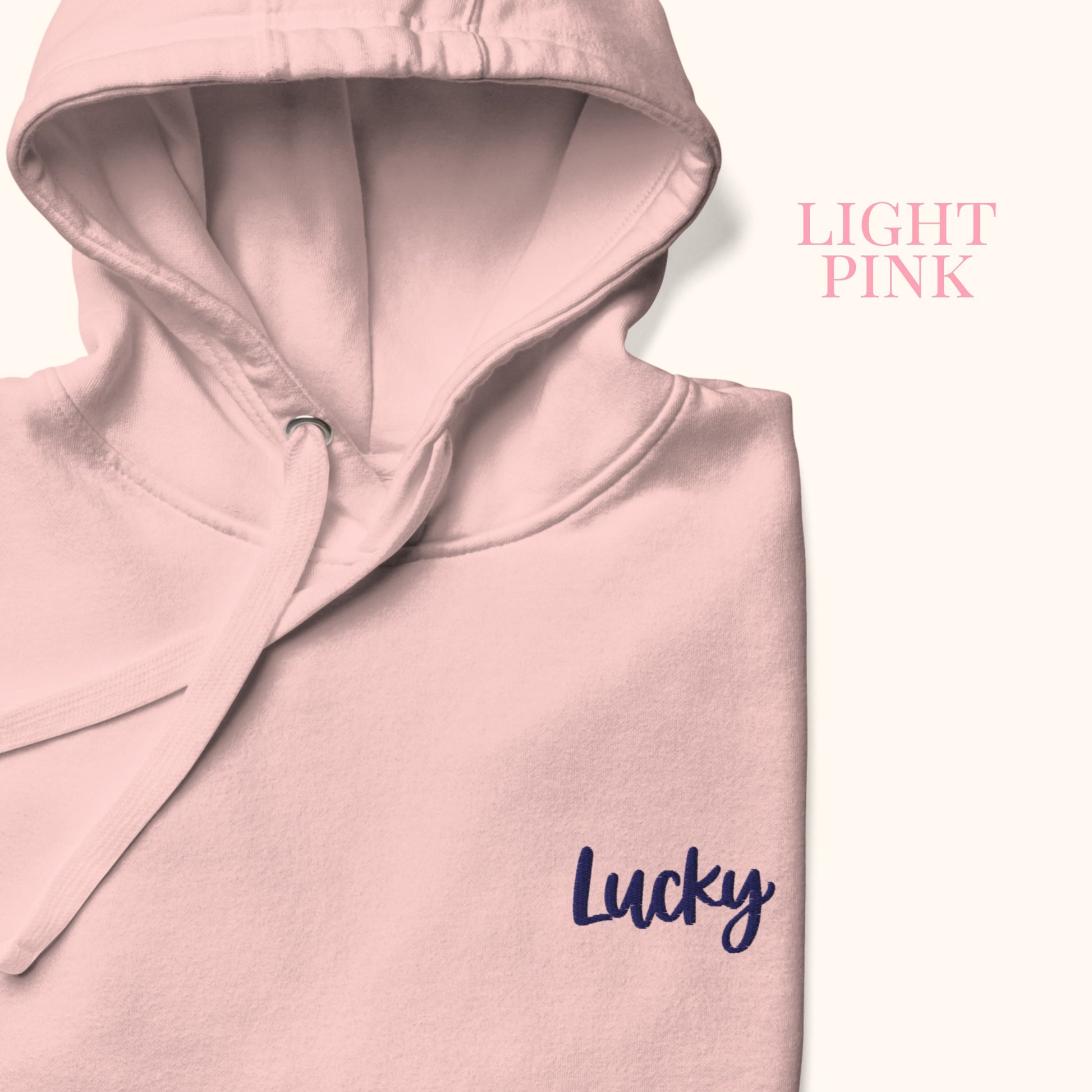 Light pink hoodie with 'Lucky' text on a white background