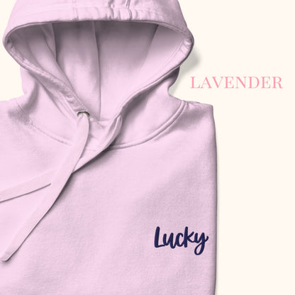 Lavender hoodie with 'Lucky' embroidery on a light cream background