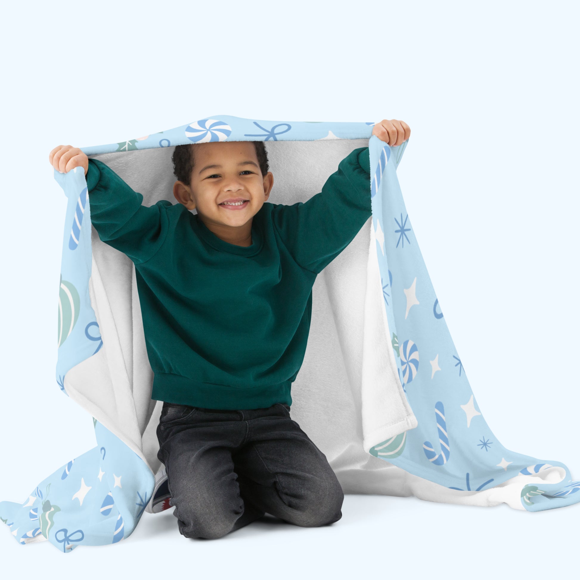 Child playing with a blue christmas blanket on a white background