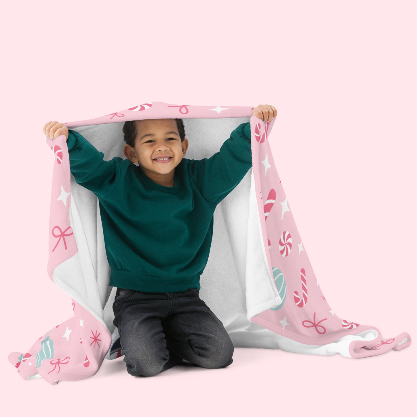Child playing with a pink christmas blanket on a white background