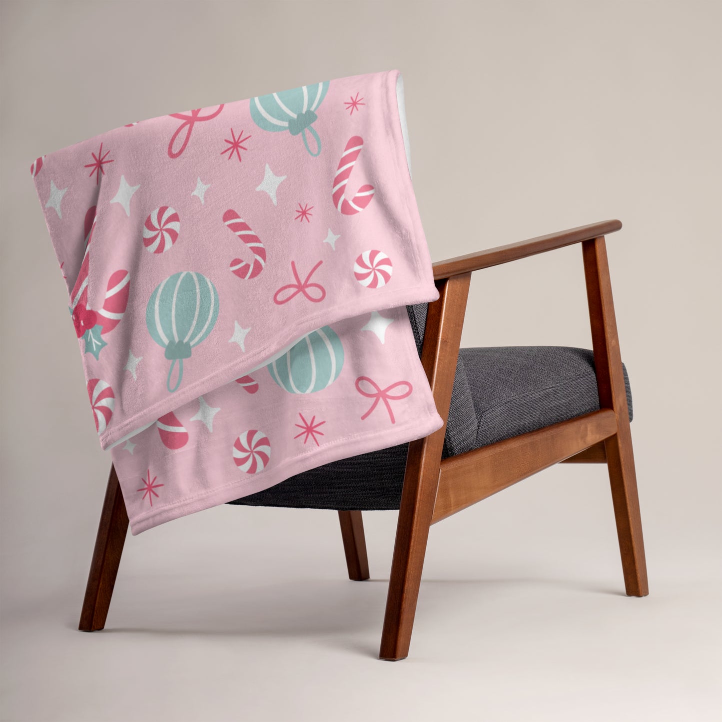 Pink christmas blanket with candy cane patterns draped over a wooden chair