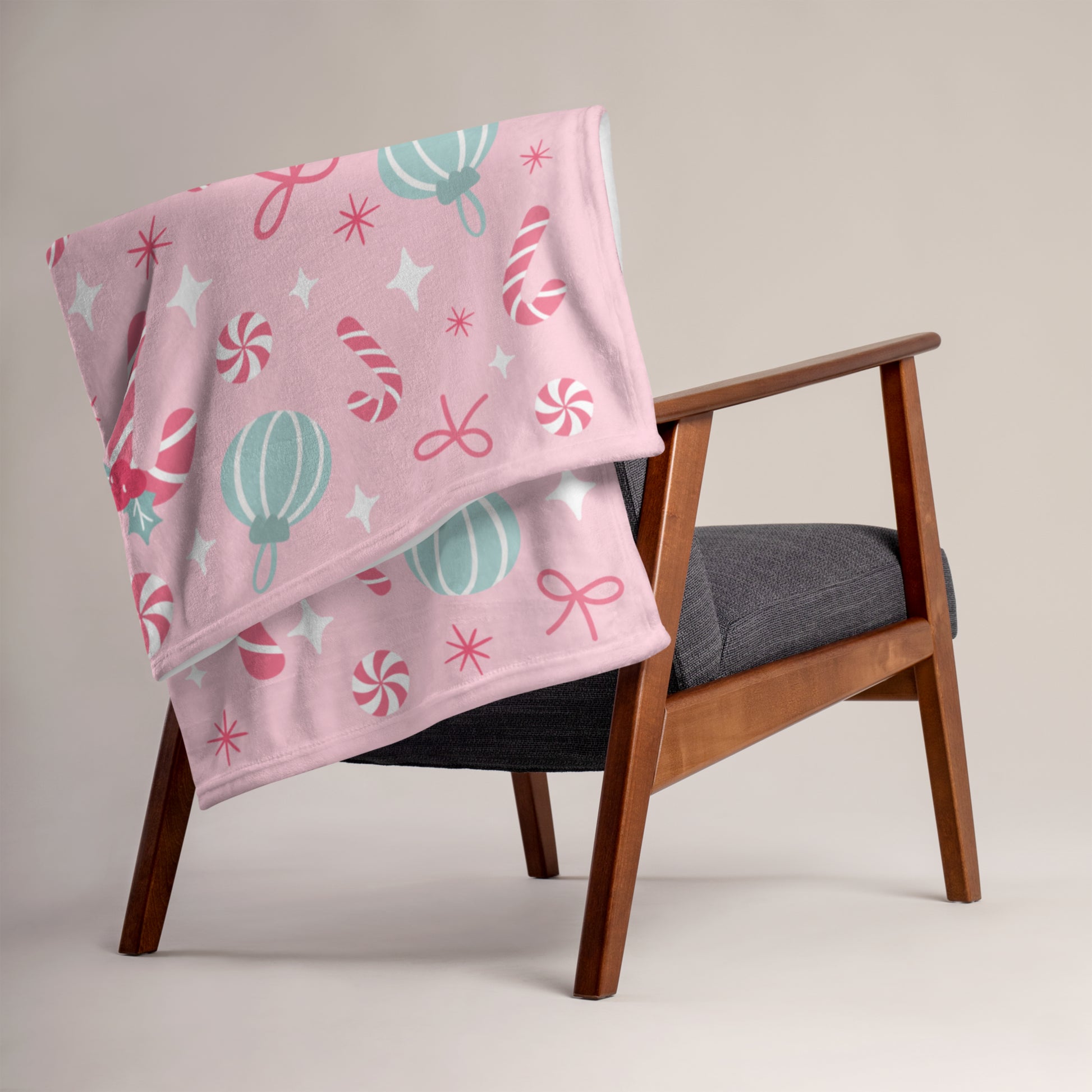 Pink christmas blanket with candy cane patterns draped over a wooden chair