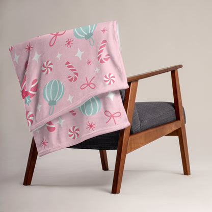 Pink christmas blanket with candy cane patterns draped over a wooden chair