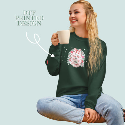 Woman wearing a green sweatshirt with a printed design, holding a mug on a light green background.