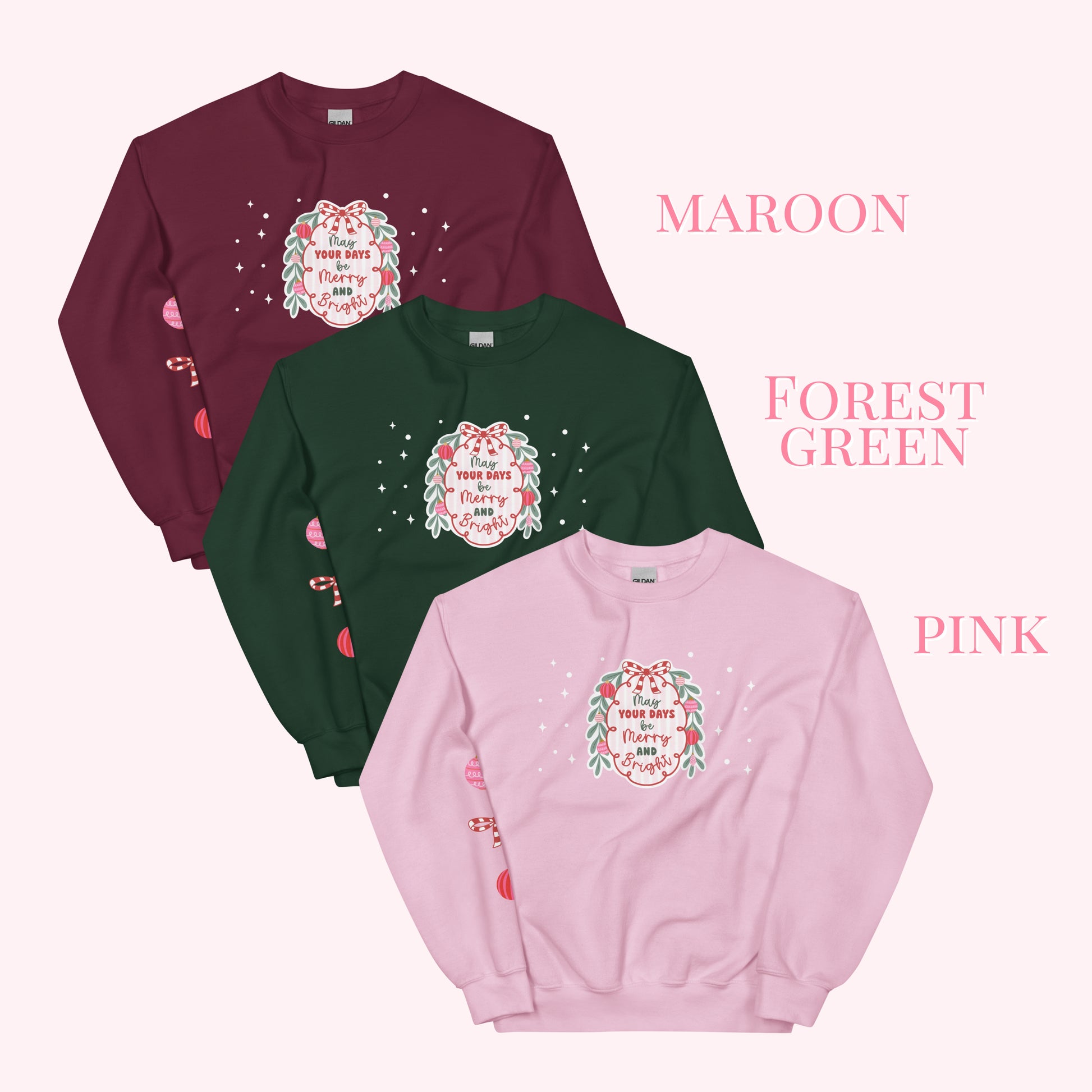 Three sweatshirts in maroon, forest green, and pink with a festive design on a white background.