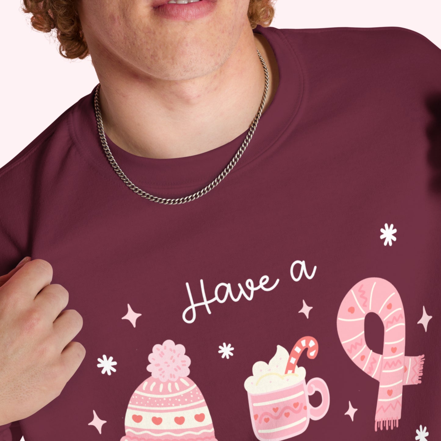 Person wearing a maroon jumper with pink winter-themed graphics and text.